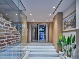 Eine moderne Lobby mit Glaswand, Backsteinwand und einer Treppe zum Empfangsbereich.