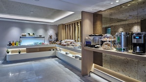 A modern breakfast buffet with a variety of food items and beverages, a coffee machine, and a decorative plant. - Four - G Hotel Premium (İstanbul)