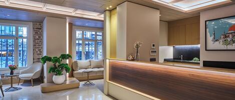 A modern reception area with a wooden reception desk, a sofa, a coffee table, and a potted plant.