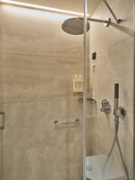 Una doccia moderna con soffione a mano, porta in vetro e porta asciugamani.