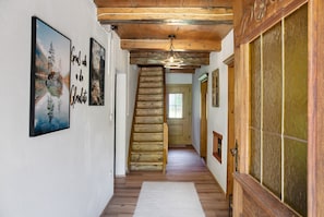 A wooden staircase leading to a room with a window, a door with a glass panel, and a wall-mounted picture frame.