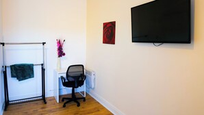 A room with a desk, chair, TV, radiator, and a towel rack. - Triple Room in Kensington with Ensuite Bathroom and Workspace (Kensington)