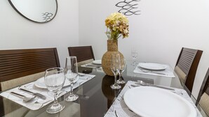 A dining table set with white plates, silverware, and wine glasses, surrounded by wooden chairs. - Comfort in Copacabana, 9 minutes from the beach | CJ202 (Rio de Janeiro)