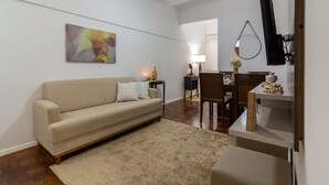 A living room with a sofa, a coffee table, a TV, and a dining area with chairs and a table. - Comfort in Copacabana, 9 minutes from the beach | CJ202 (Rio de Janeiro)