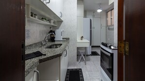 A compact kitchen with granite countertops, a sink, a stove, and a refrigerator. - Comfort in Copacabana, 9 minutes from the beach | CJ202 (Rio de Janeiro)