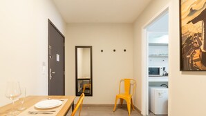 Un coin repas avec une table en bois dressée pour deux personnes, une chaise, un petit réfrigérateur et un four à micro-ondes en arrière-plan.