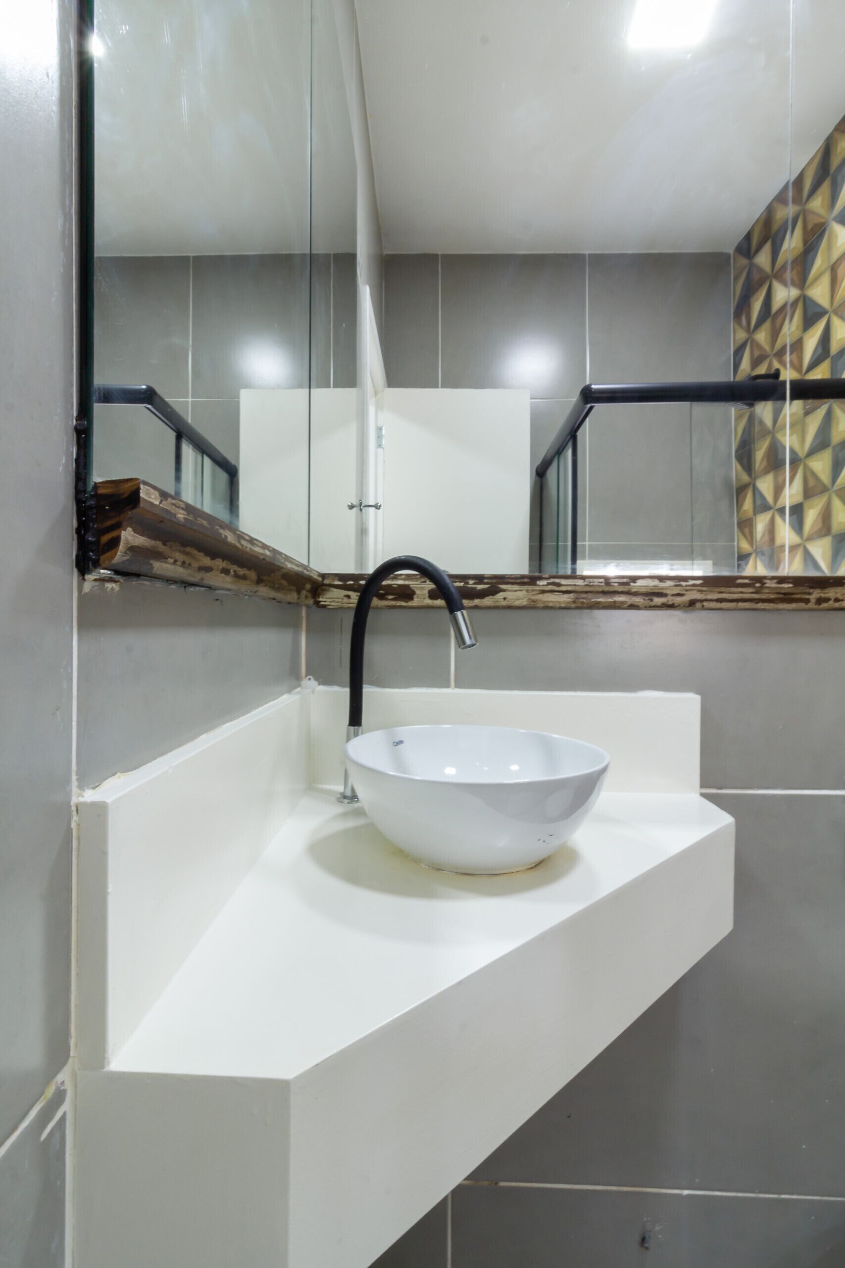 Un baño moderno con un lavamanos blanco, un grifo negro y un espejo encima.
