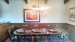 A dining area with a wooden table and chairs, a chandelier, and framed artwork on the walls. - CR-22 Harbeson Haven Peaceful 4 BR Chalet-Style Home Very well maintained (Beech Mountain)