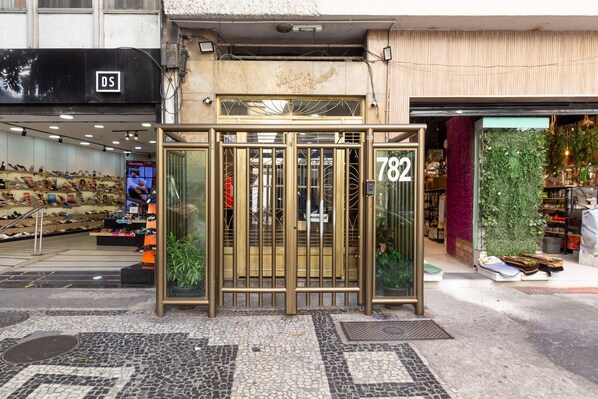 A storefront with a metal gate, a shoe display, and a green wall with plants.