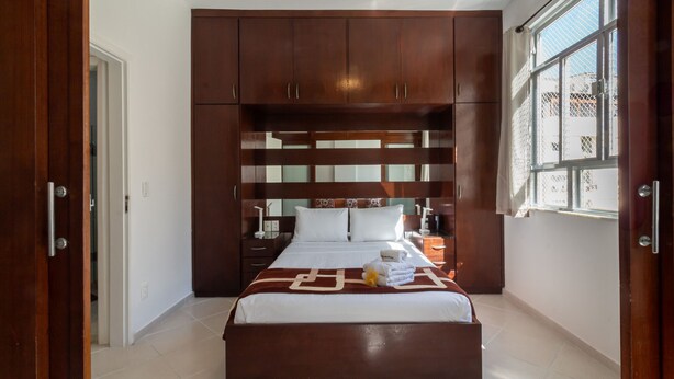 A hotel room with a large bed, wooden headboard, and a window with a view. - 5 minutes from Copacabana beach | NSC906 (Rio de Janeiro)