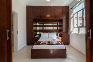A hotel room with a large bed, wooden headboard, and a window with a view.