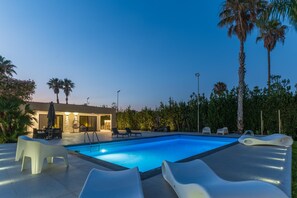 A swimming pool with lounge chairs and a building with outdoor seating. - Nereide, luxury villa in Sicily with pool, near the beach (Punta Secca)