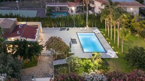 En boligejendom med swimmingpool, udendørs siddepladser og en velholdt have.