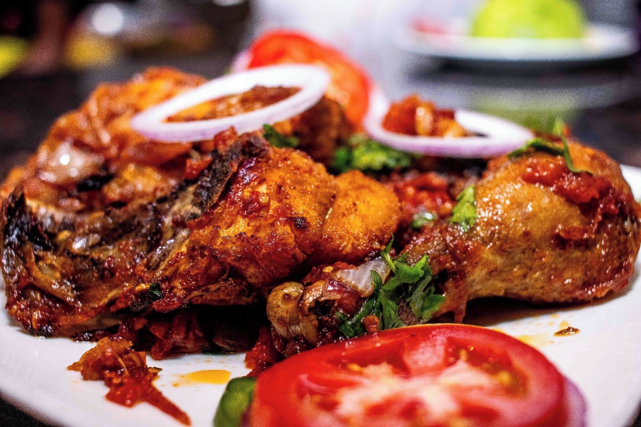 Un plato de pollo a la parrilla con verduras y una rodaja de tomate.