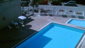 A swimming pool with a tiled deck, a few lounge chairs, and a small garden area with plants. - Beautifully Renovated Flat With Shared Pool (Rosolina)