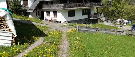 Ein zweistöckiges Haus mit geneigtem Dach, einem Balkon und einem Steinunterbau.