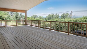 Una terraza de madera con barandilla, con vistas a un paisaje verde exuberante y líneas eléctricas.