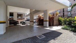 Eine Parkgarage mit zwei parkenden Autos, einem überdachten Gang und einem Gebäude mit Backsteinwand und Pflanzen.