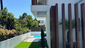 A modern two-story building with a balcony, a swimming pool, and a fenced garden area. - Holiday home with pool 15 minutes walk from the beach and 5 minutes from Aroeira golf course (Almada)
