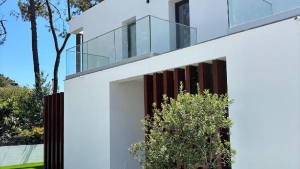 A modern building with a flat roof, a glass balcony, and a small tree in the foreground. - Holiday home with pool 15 minutes walk from the beach and 5 minutes from Aroeira golf course (Almada)