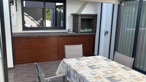 A compact kitchen with a built-in oven, a dining table with a patterned tablecloth, and a sliding glass door. - Holiday home with pool 15 minutes walk from the beach and 5 minutes from Aroeira golf course (Almada)