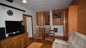 Una sala de estar acogedora con televisión, muebles de madera y un cuadro en la pared.