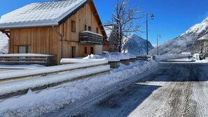 Een houten gebouw met een sneeuwbedekte dak, een houten terras en een berg op de achtergrond.