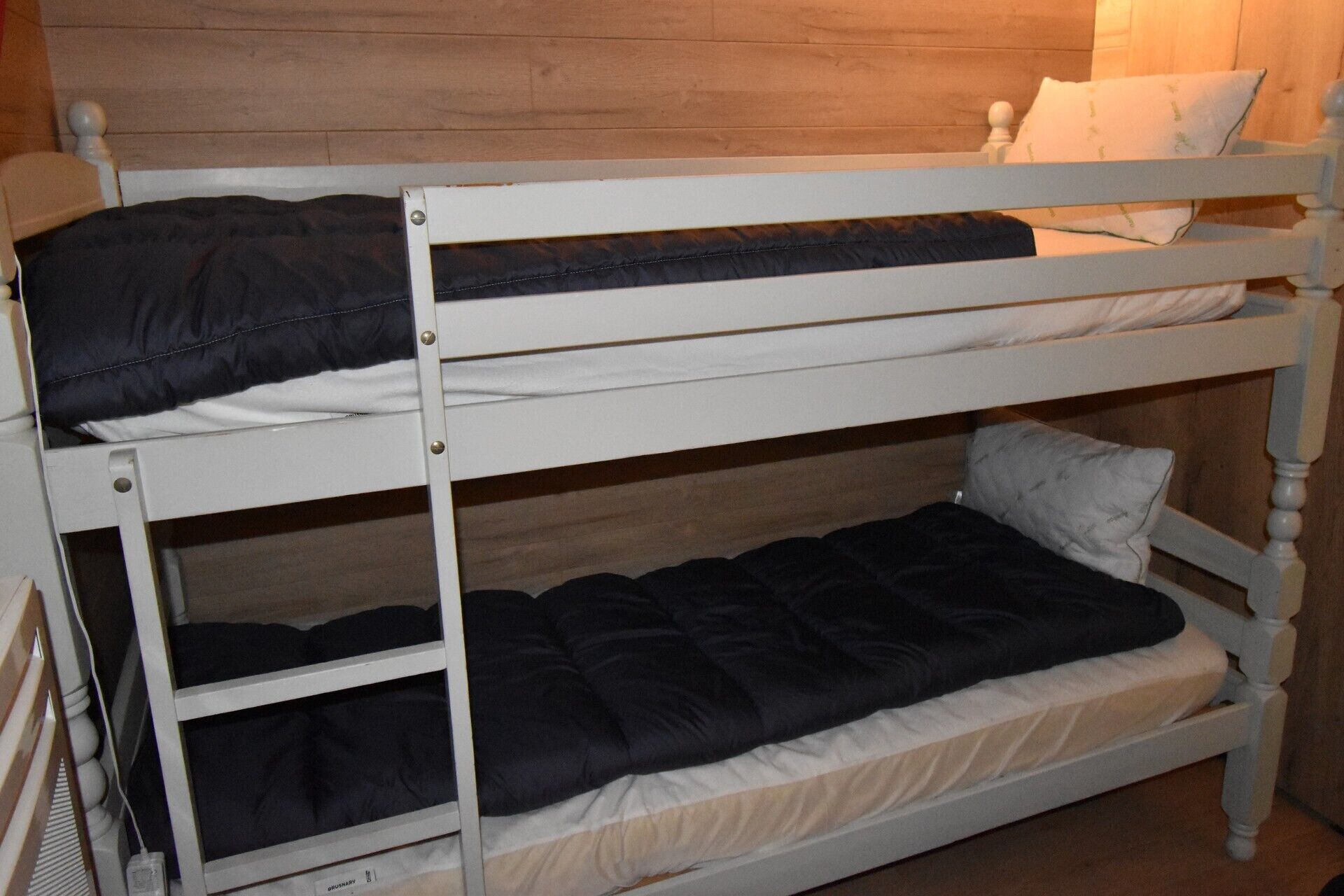 A bunk bed with two levels, each with a pillow and a blanket.