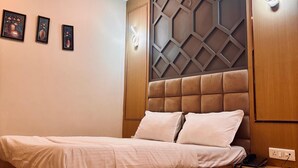 A bedroom with a wooden bed, a ceiling fan, and wall-mounted lights. - Hotel Ambrosia Delhi Airport (New Delhi)