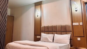 A modern bedroom with a large bed, a ceiling fan, and built-in lighting. - Hotel Ambrosia Delhi Airport (New Delhi)