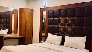 A bedroom with a large bed, wooden wardrobe, and a mirror. - Hotel Ambrosia Delhi Airport (New Delhi)