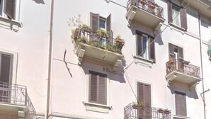 A multi-story building with balconies, a wooden door, and parked cars. - San Nicolicchio (Taranto)