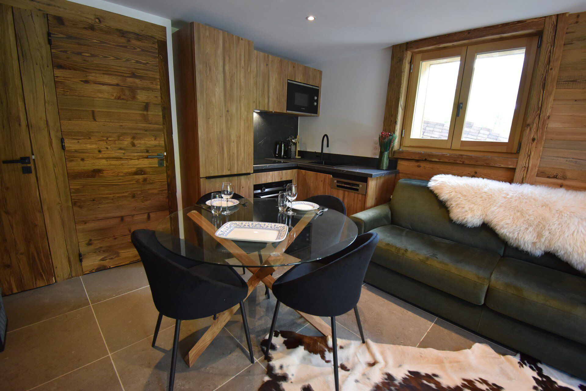 A compact living space with a dining area, kitchenette, and a sofa with a fur throw.