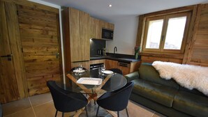 A compact living space with a dining area, kitchenette, and a sofa with a fur throw. - Flocon 2 - One Bedroom Apartment, Sleeps 4 (Vaujany)