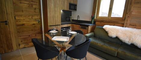 A compact living space with a dining area, kitchenette, and a sofa with a fur throw.