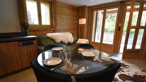 A dining area with a glass table, two chairs, a sofa with a fur throw, and a cowhide rug. - Flocon 2 - One Bedroom Apartment, Sleeps 4 (Vaujany)
