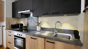 Una cocina moderna con armarios negros, un lavamanos de acero inoxidable y un horno empotrado.
