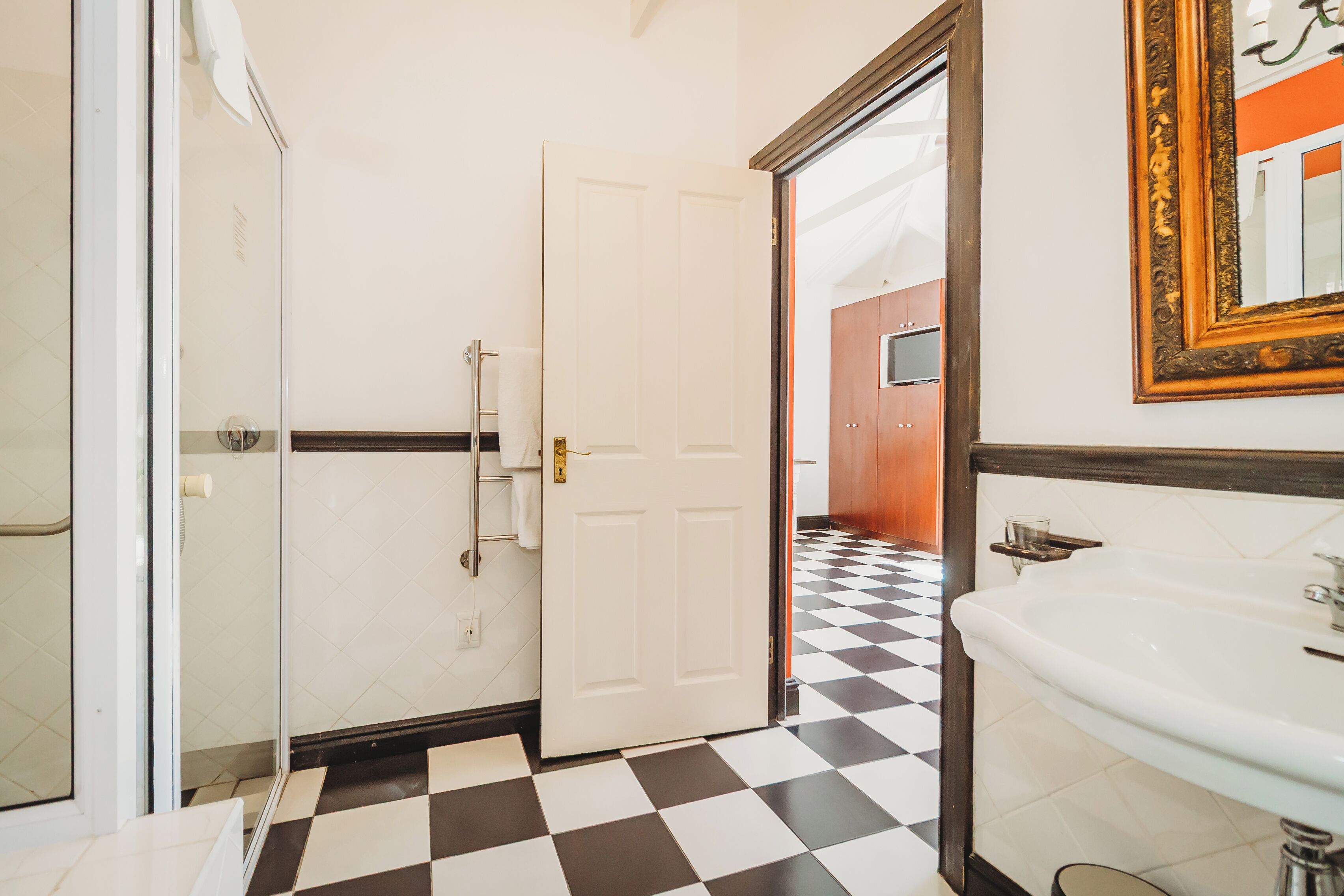 A bathroom with a checkered floor, a white sink, and a glass shower enclosure.