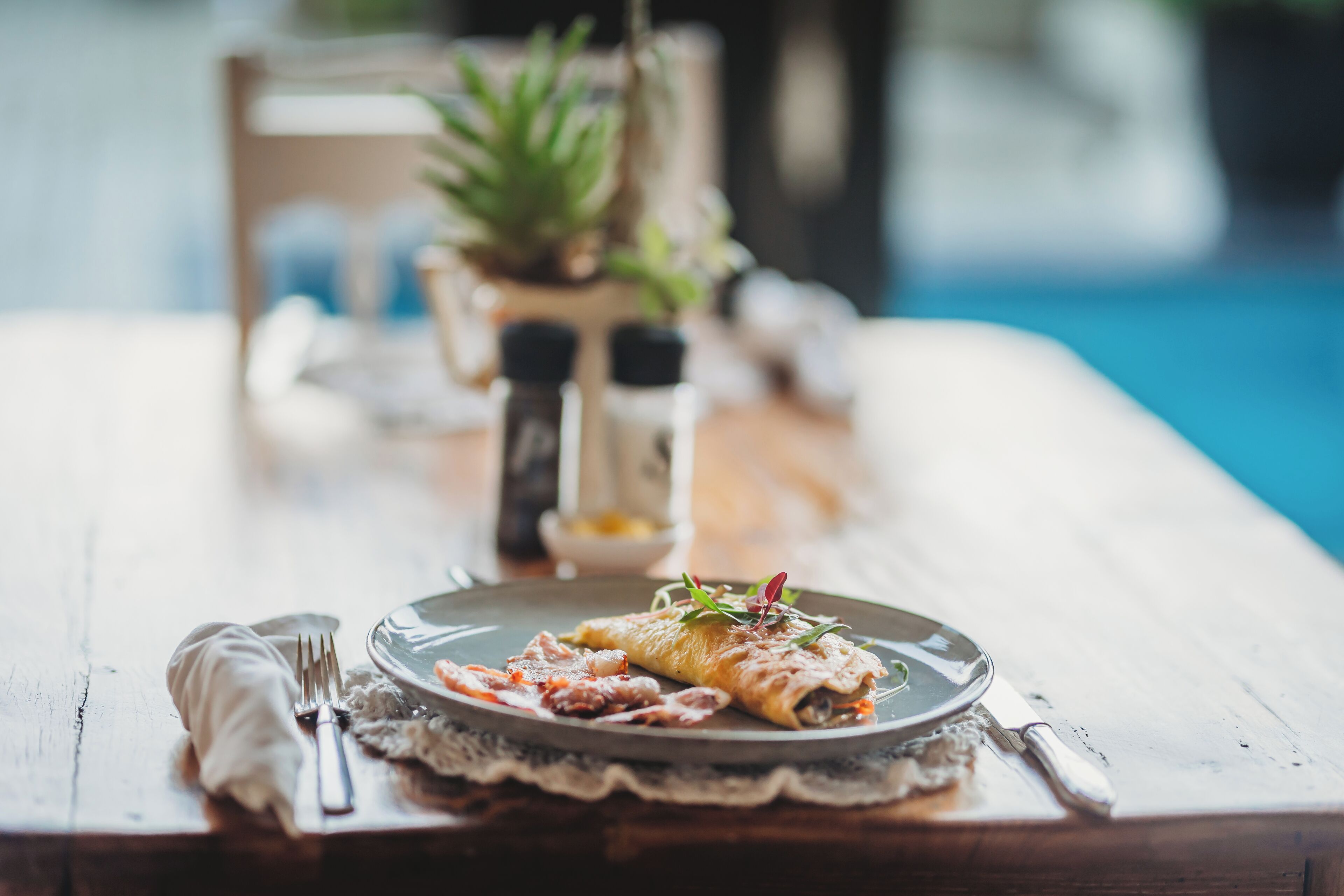 A dining table with a plate of food, cutlery, and a napkin.