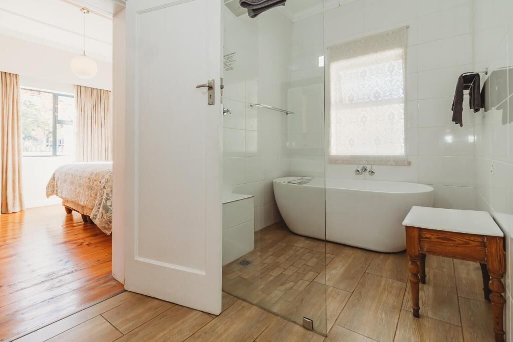 A modern bathroom with a glass-enclosed shower, a freestanding bathtub, and a wooden vanity.