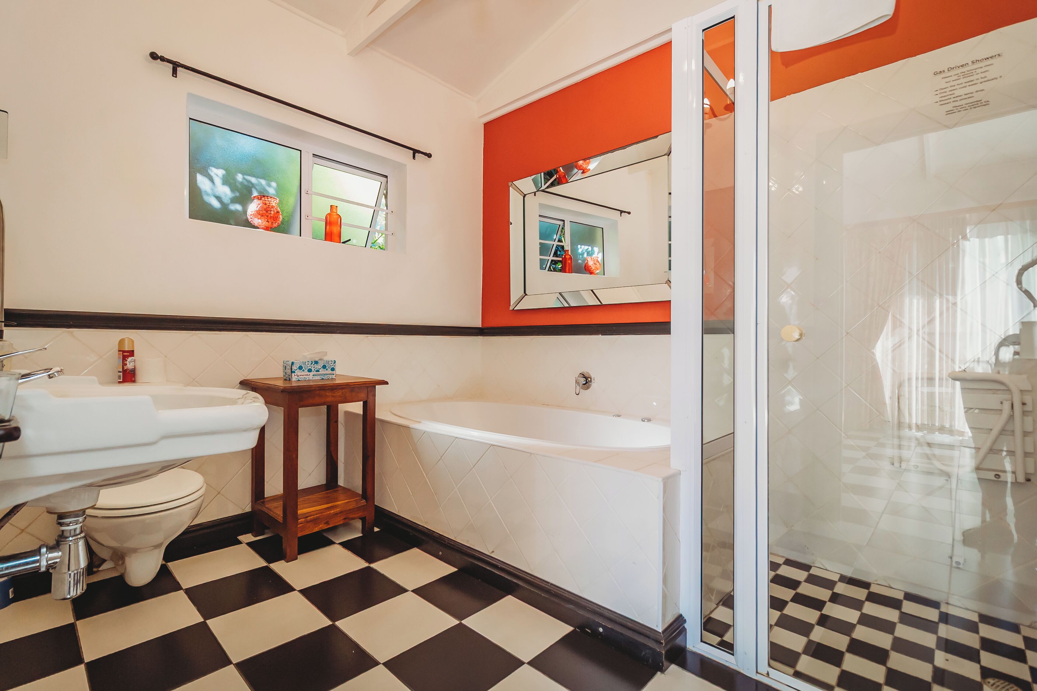 Une salle de bain avec un carrelage à motifs, un lavabo blanc, une baignoire et une cabine de douche en verre.