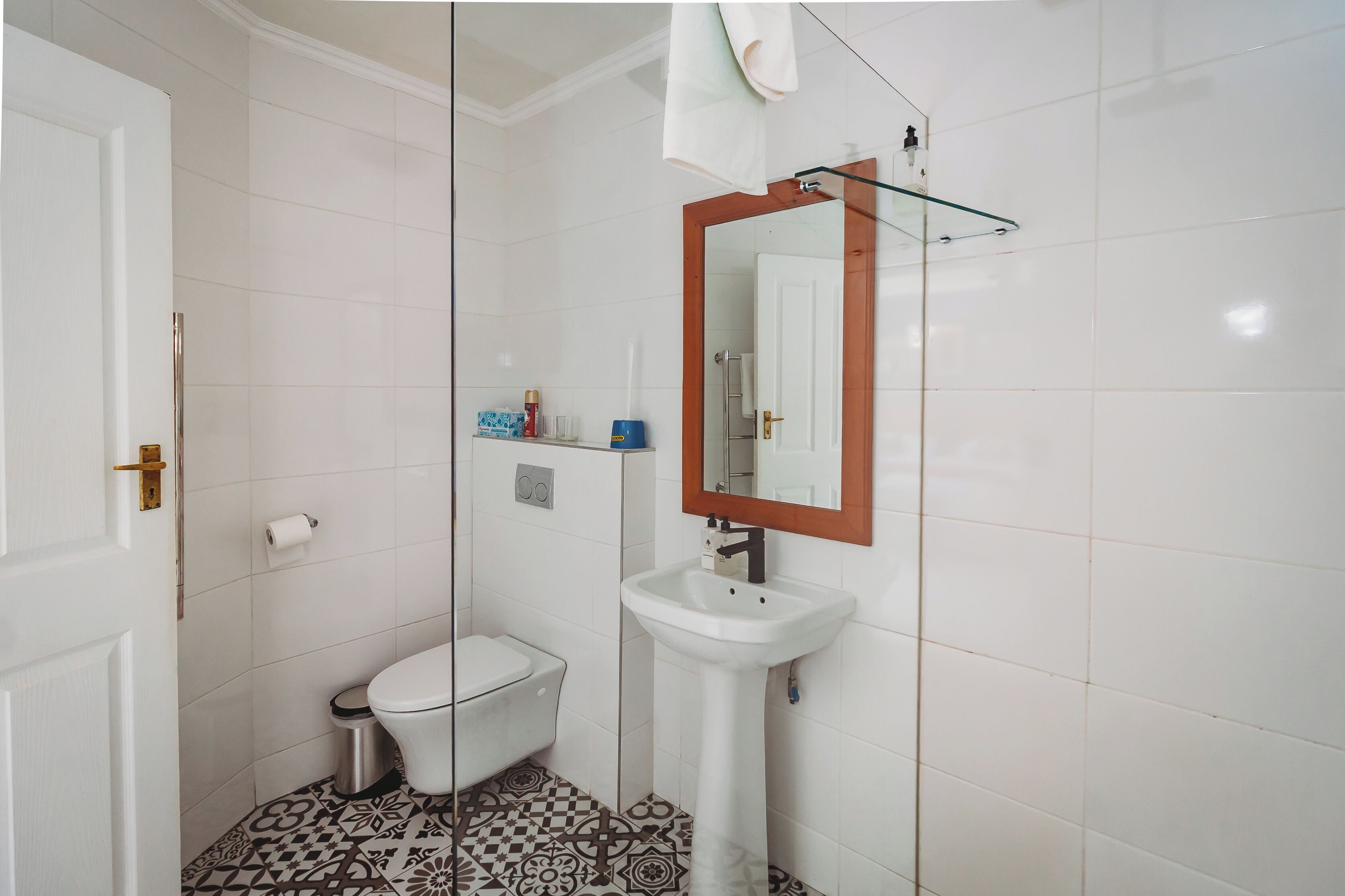 A bathroom with a toilet, sink, and mirror.