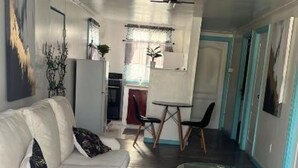A modern living room with a white sofa, a glass coffee table, and a geometric patterned rug.