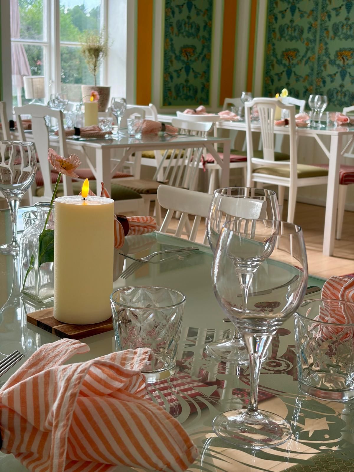 A dining area with tables set for a meal, featuring clear glassware and striped napkins.