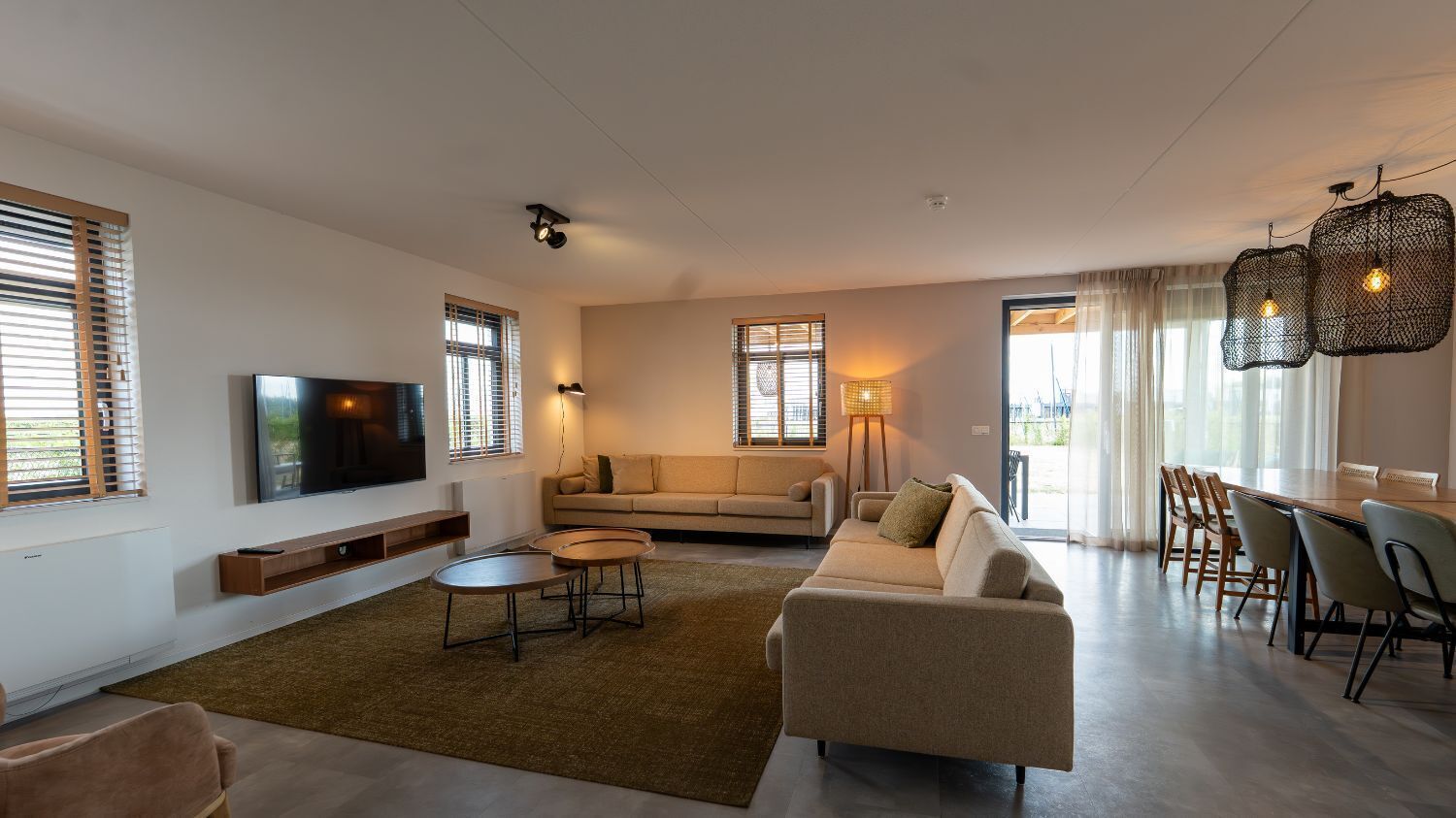 Ein modernes Wohnzimmer mit Flachbildfernseher, einer Couch, einem Couchtisch und einem Essbereich mit Stühlen.