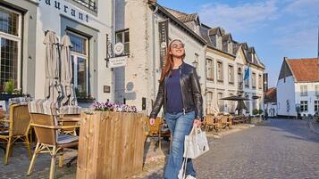 A woman standing in front of a building with a sign that reads "RESTAURANT LA VILLE BANCHE."