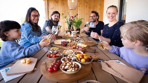 A group of people seated around a wooden table with various food items and drinks, suggesting a casual dining or social gathering. - Harbor View 12p - Six Bedroom Villa, Sleeps 12 (Thorn)