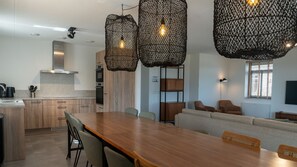 Een moderne keuken met houten kastjes, een roestvrijstalen afzuigkap en een eethoek met een houten tafel en stoelen.