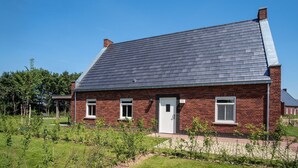 A single-story brick house with a dark shingled roof, a white door, and two windows. - Harbor View 12p - Six Bedroom Villa, Sleeps 12 (Thorn)