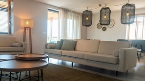 Un salon moderne avec un canapé, deux tables rondes et des luminaires suspendus.
